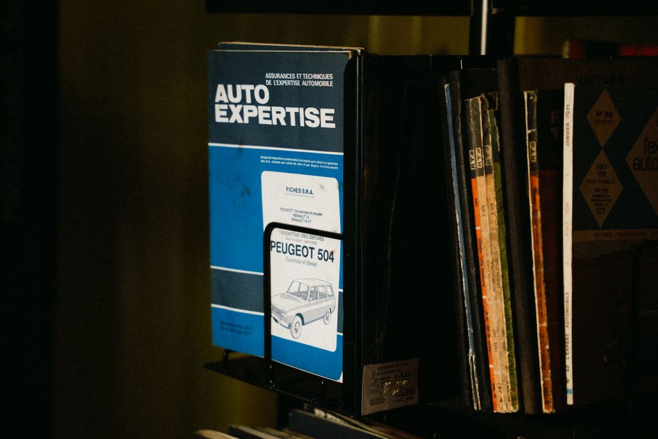 Vintage Auto Expertise book and Peugeot manuals neatly on a shelf.
